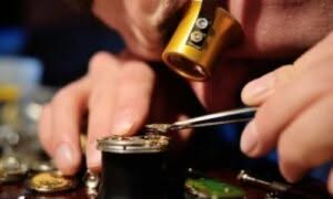orologiaio che con lente ripara il meccanisco di un orologio